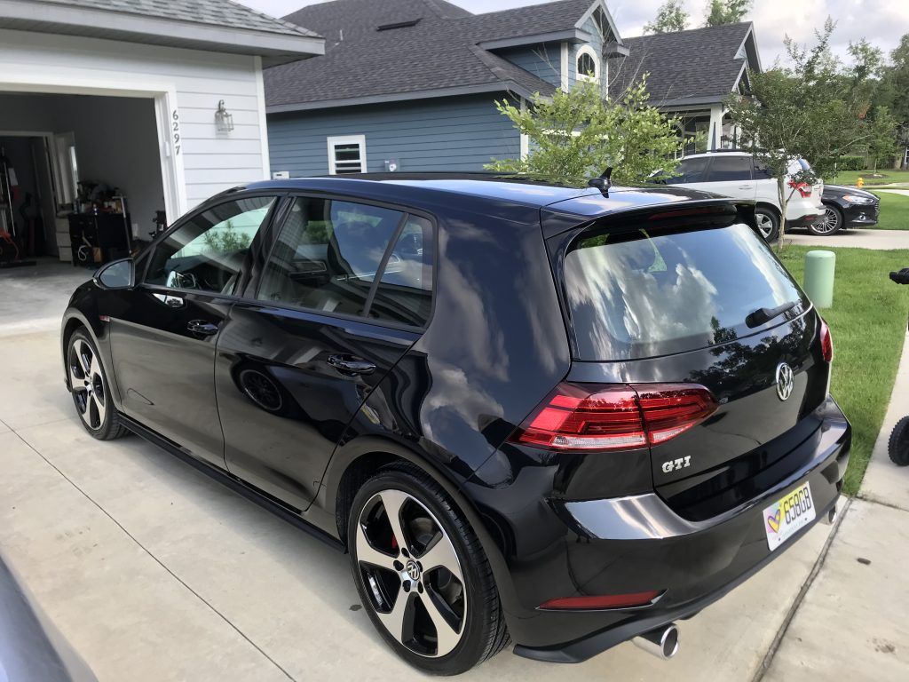 A black volkswagen golf is parked in front of a house.