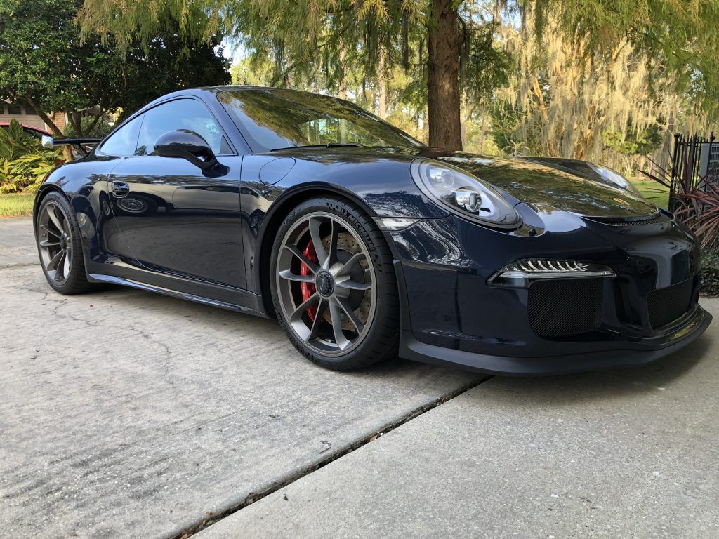 A black porsche 911 gt3 is parked on the side of the road.
