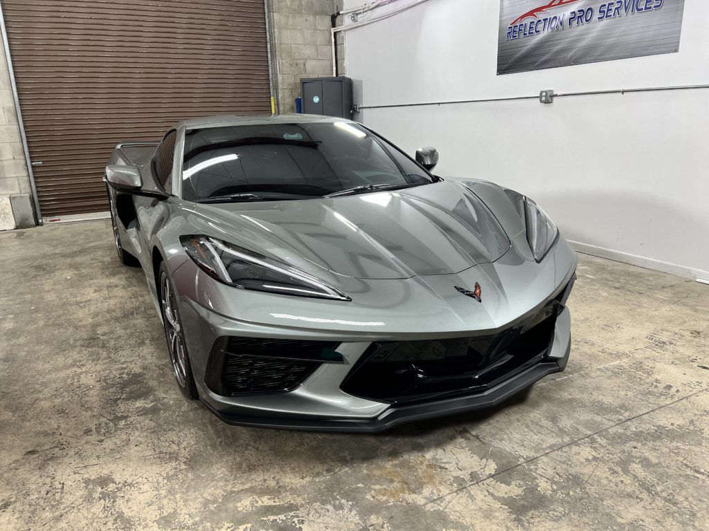 A gray sports car is parked in a garage.