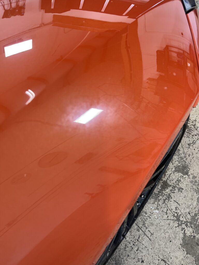 A close up of a red car 's hood in a garage.