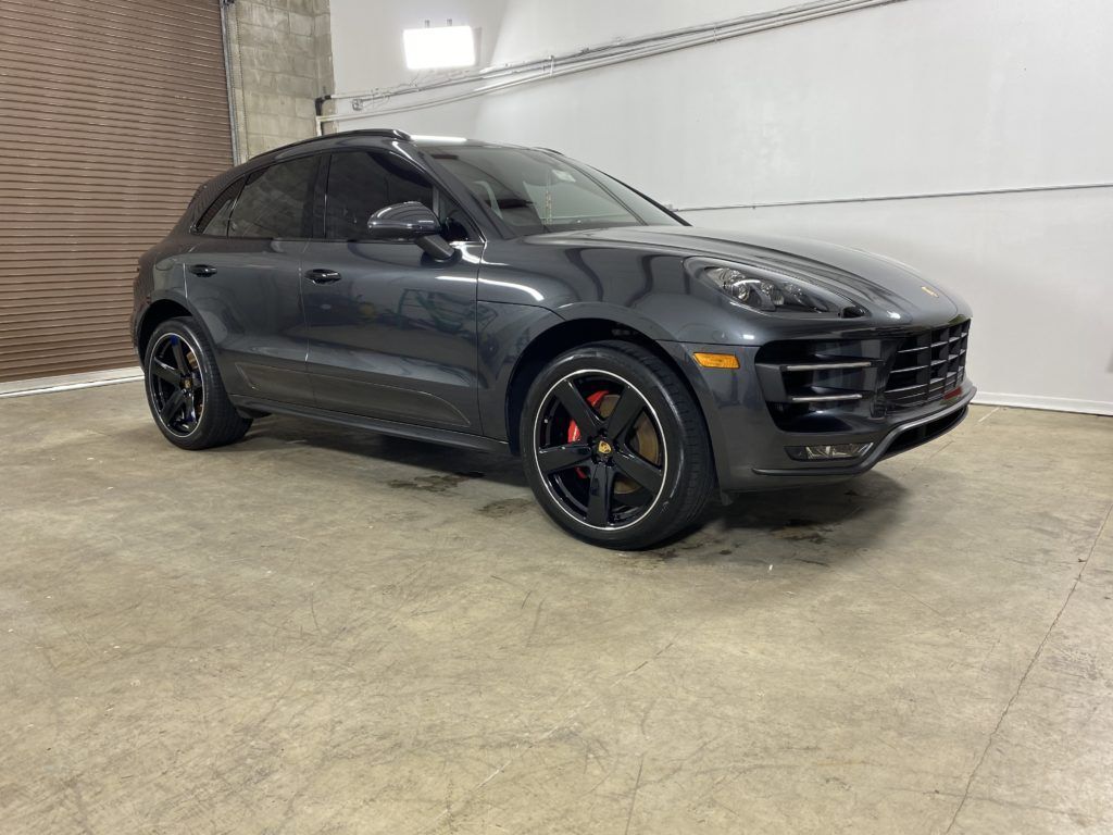 A gray porsche macan turbo is parked in a garage.