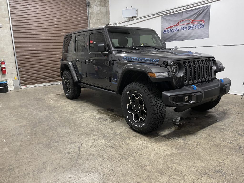 A jeep wrangler is parked in a garage next to a garage door.