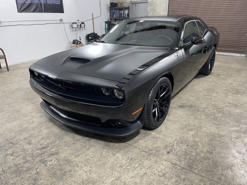 A black dodge challenger is parked in a garage.