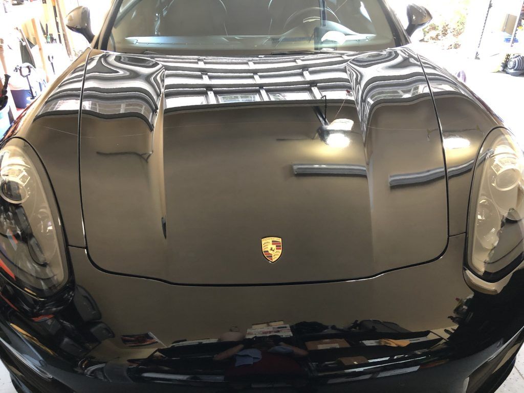 The front of a black porsche cayenne is sitting in a garage.