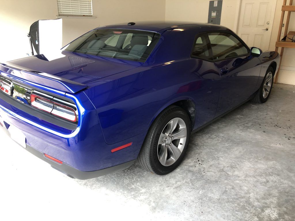A blue dodge challenger is parked in a garage.
