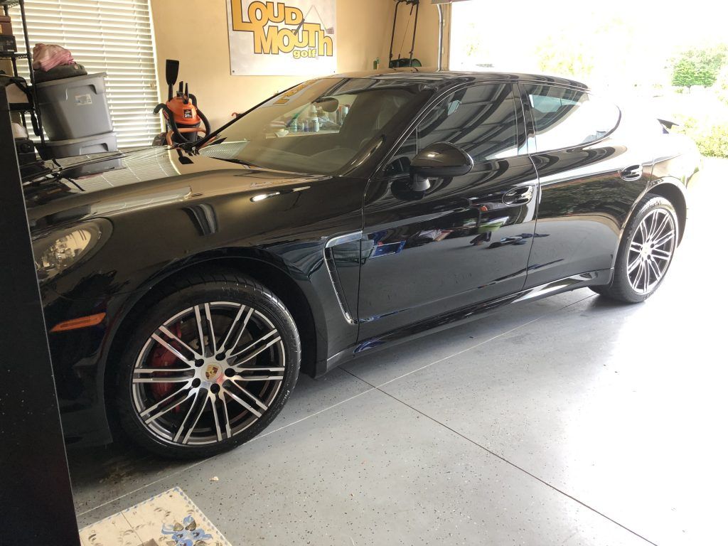 A black sports car is parked in a garage.