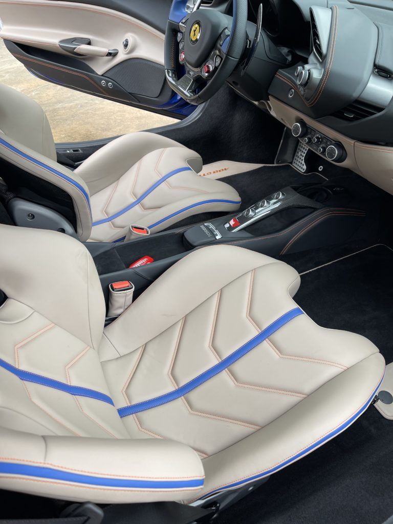 The interior of a ferrari sports car with blue stripes on the seats