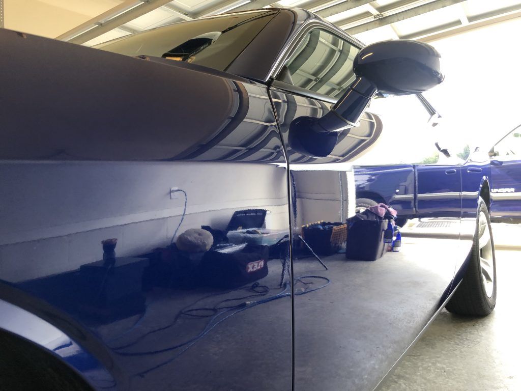 A blue car is parked in a garage with the door open