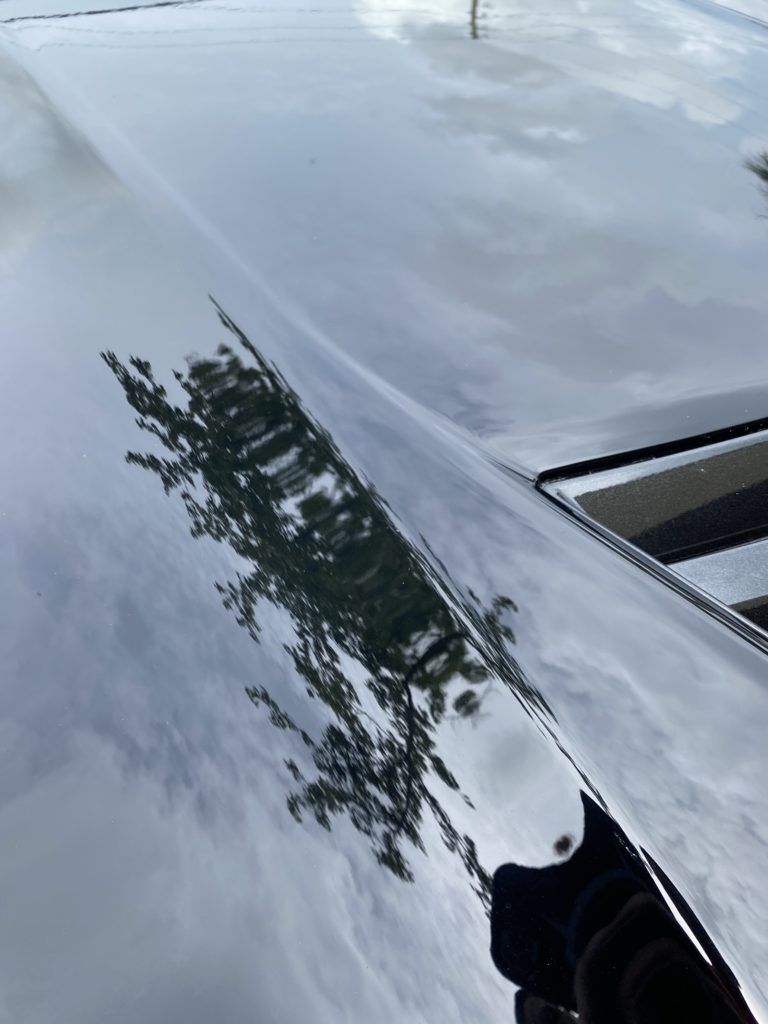 The hood of a car is reflected in the snow