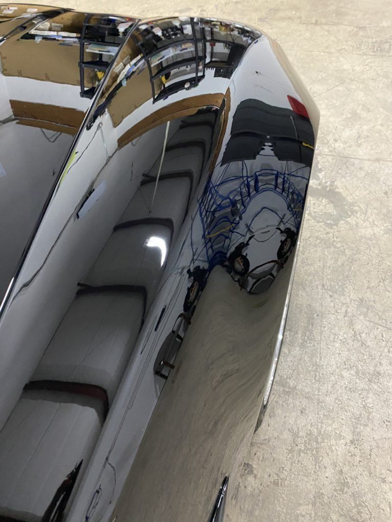 A close up of a car hood with a reflection of a person in it