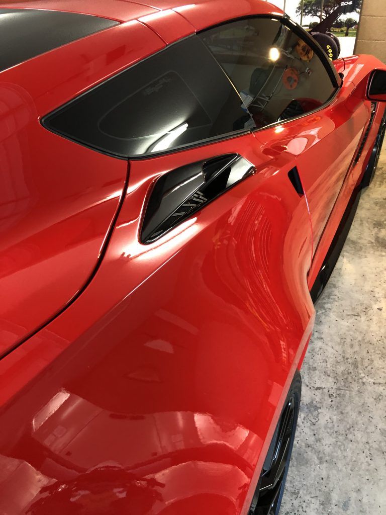 A red sports car is parked in a garage.