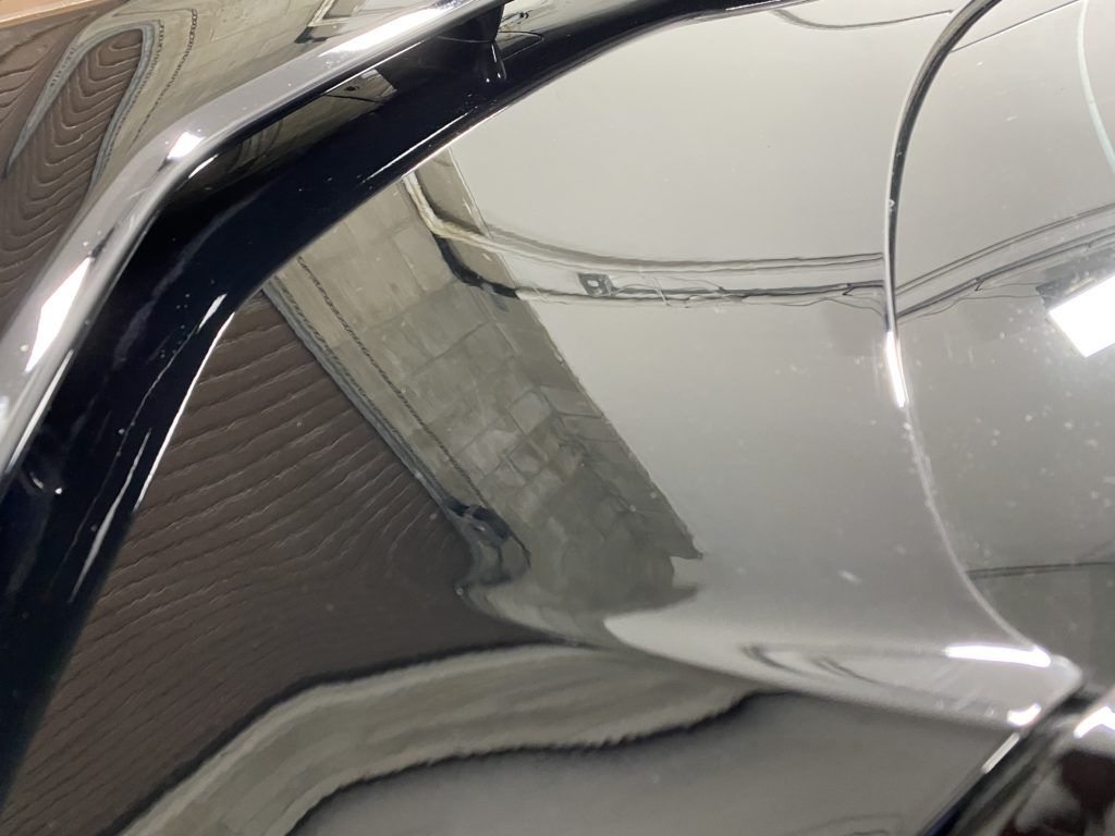 A close up of a car hood with a reflection of a building