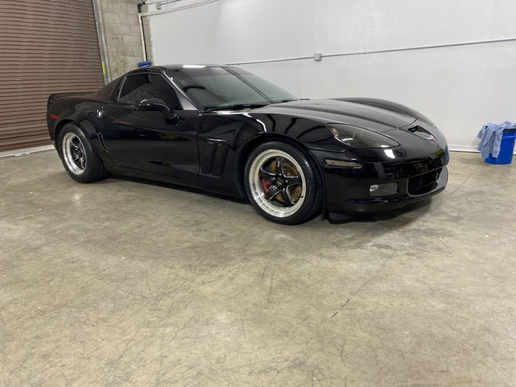A black sports car is parked in a garage.