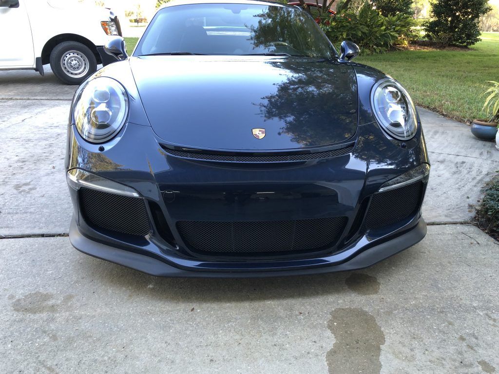 A black porsche 911 gt3 rs is parked in a driveway.