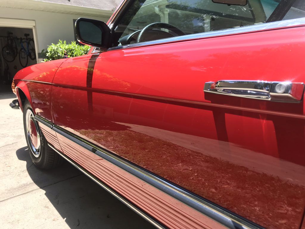 A red car is parked in front of a garage.