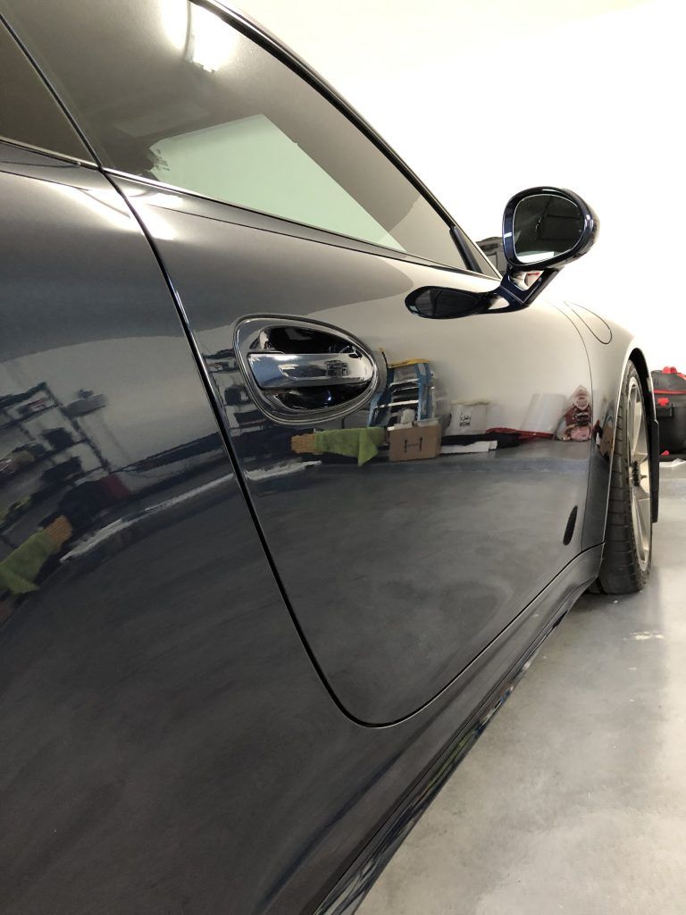 A black sports car is parked in a garage.
