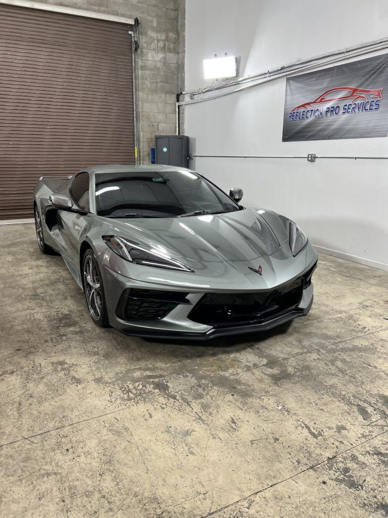 A gray corvette is parked in a garage.