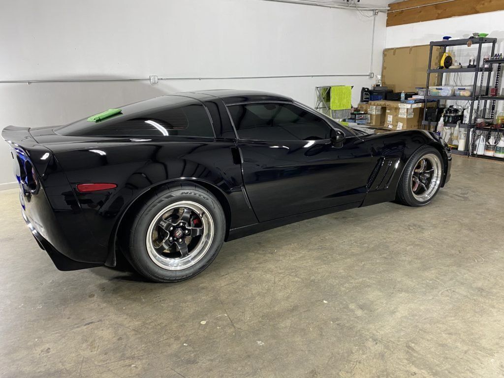 A black sports car is parked in a garage.