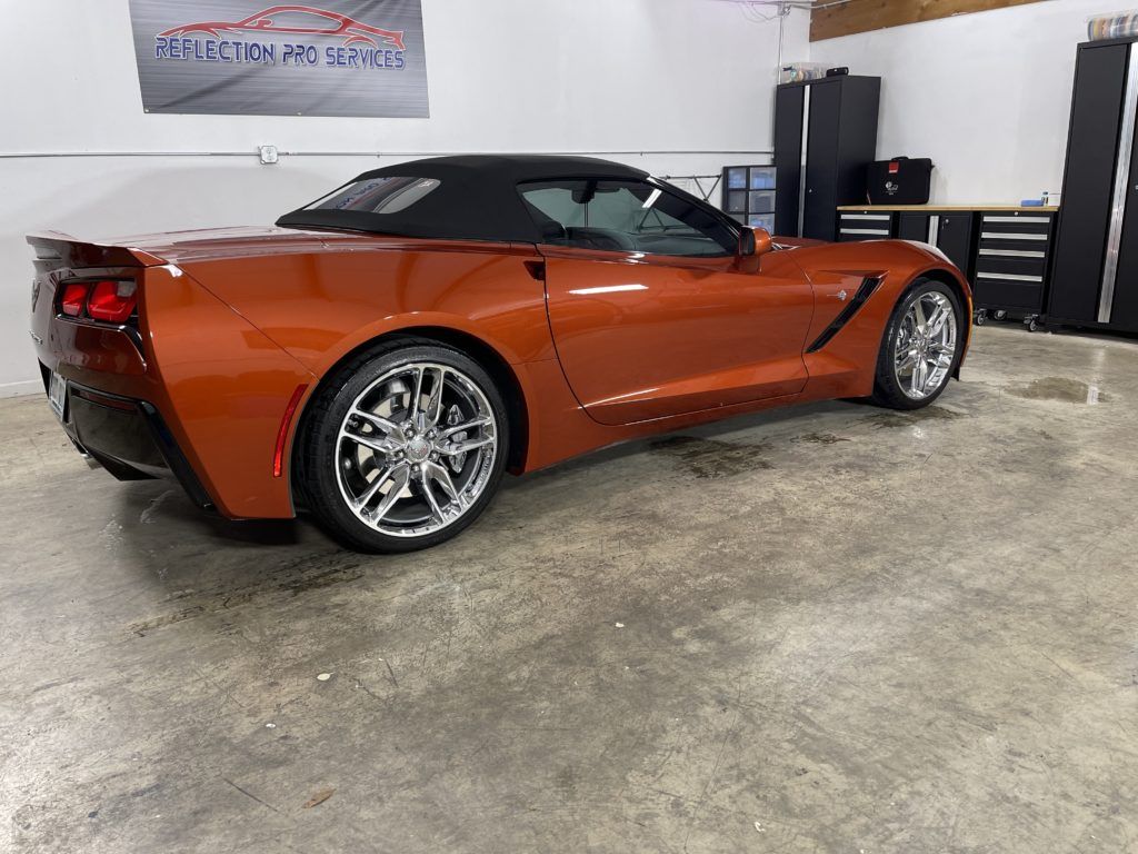 A red corvette convertible is parked in a garage.