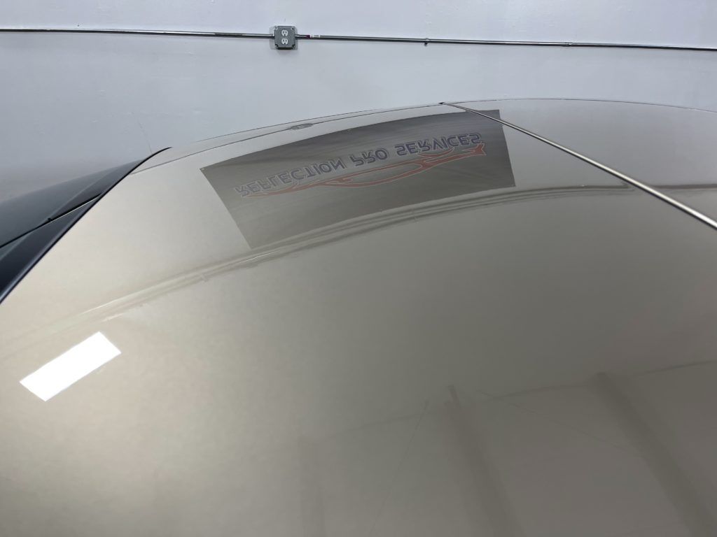 A close up of a car windshield with a reflection of a building in it