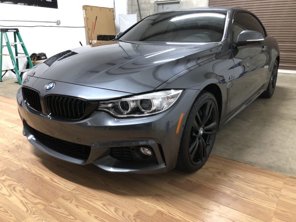 A gray bmw 4 series coupe is parked in a garage.