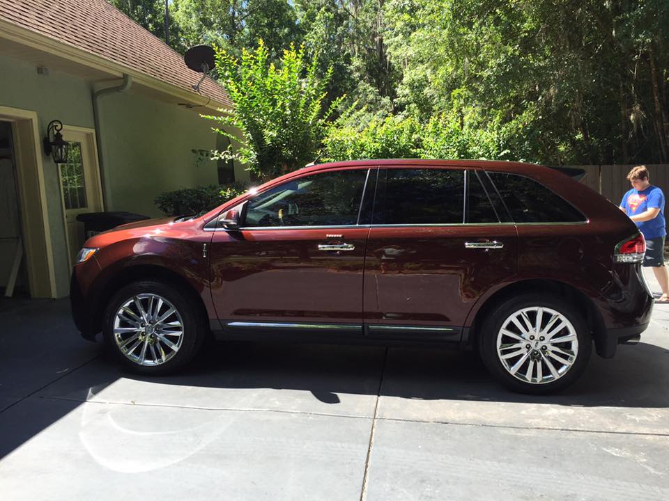A red suv is parked in a driveway next to a house.