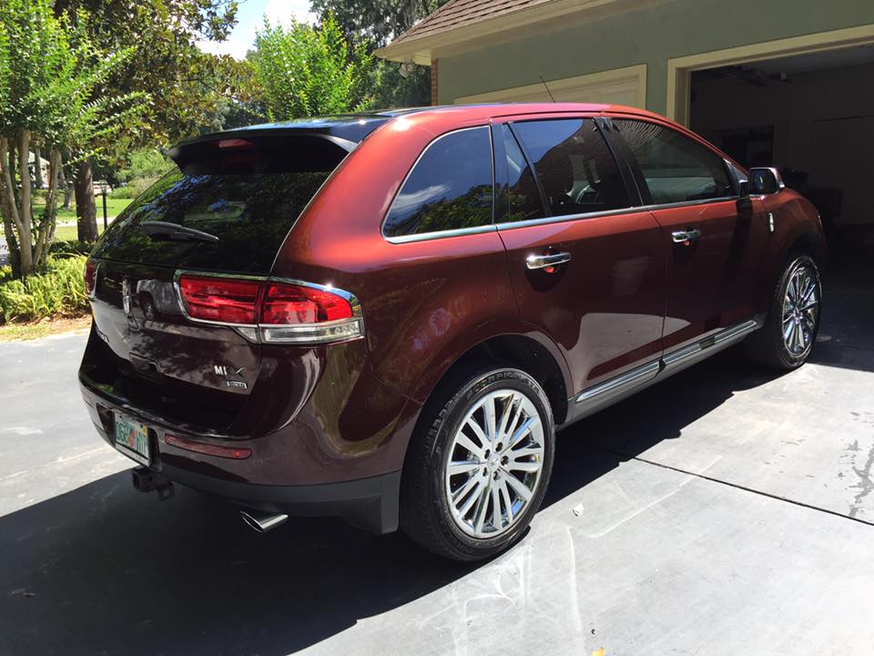 A red lincoln lx is parked in a driveway next to a garage.