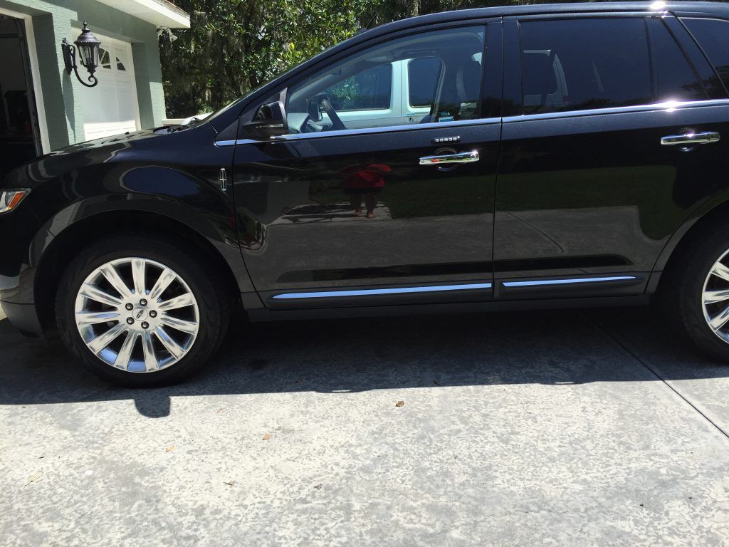 A black suv is parked in a driveway in front of a house.
