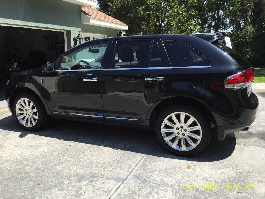 A black suv is parked in a driveway in front of a garage.