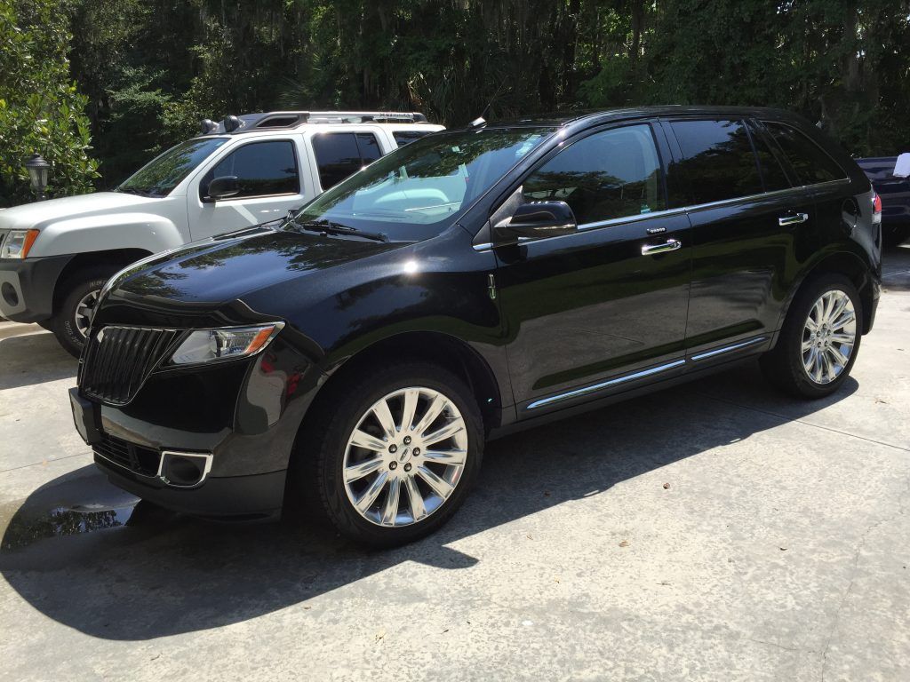 A black lincoln continental is parked in a parking lot next to a white suv.