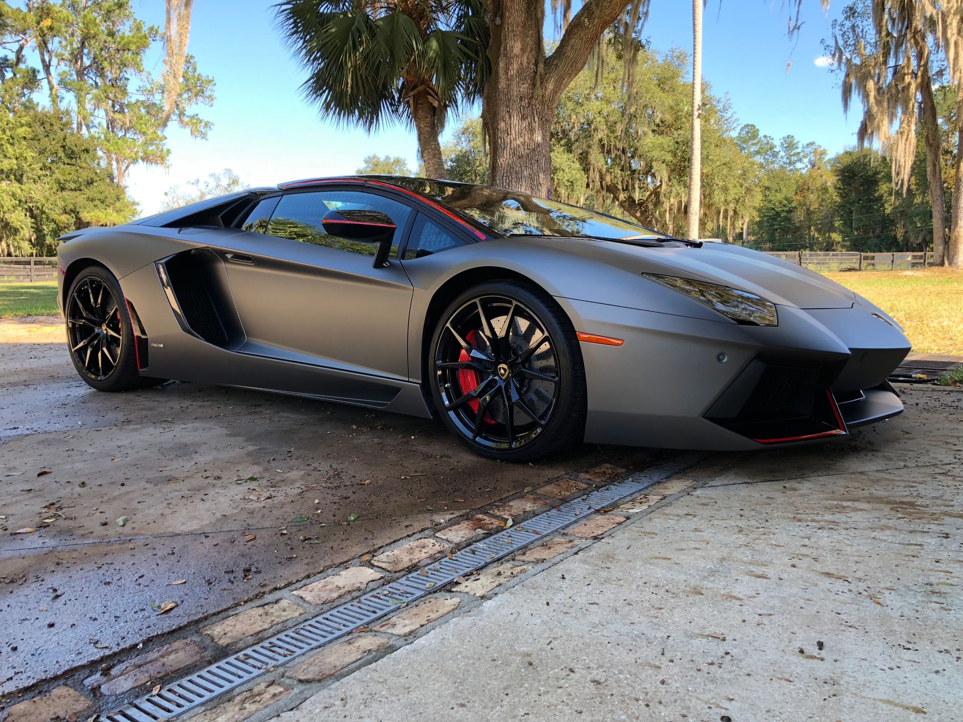 A gray lamborghini aventador is parked on the side of the road.
