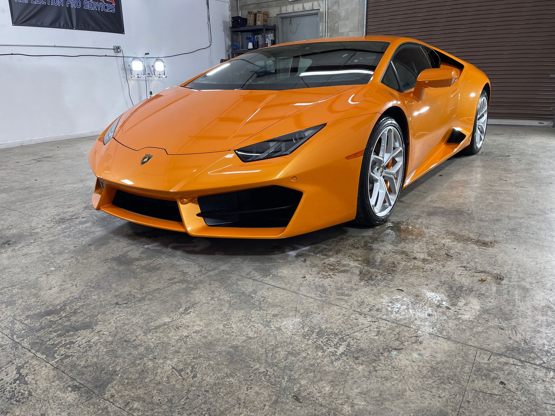 An orange lamborghini huracan is parked in a garage.