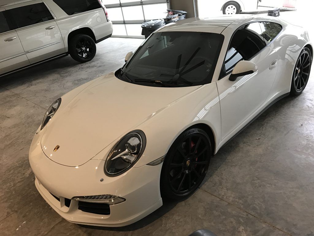 A white porsche 911 is parked in a garage.