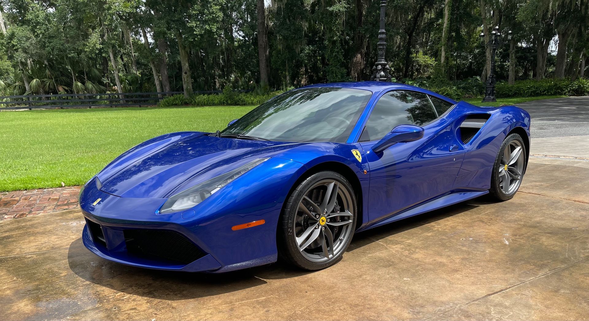 A blue ferrari 488 gtb is parked in a driveway.