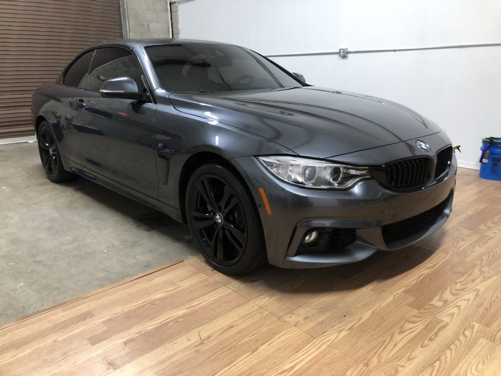 A bmw is parked in a garage with a wooden floor.