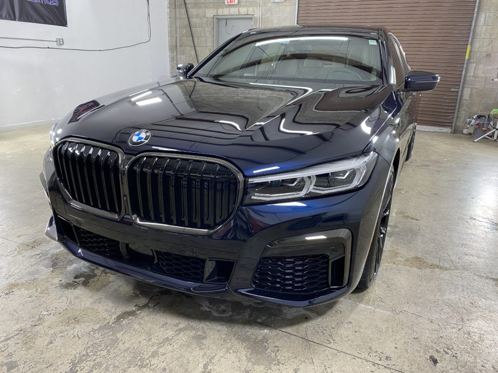 A black bmw 750li is parked in a garage.