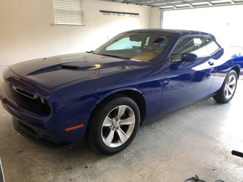 A blue dodge challenger is parked in a garage.