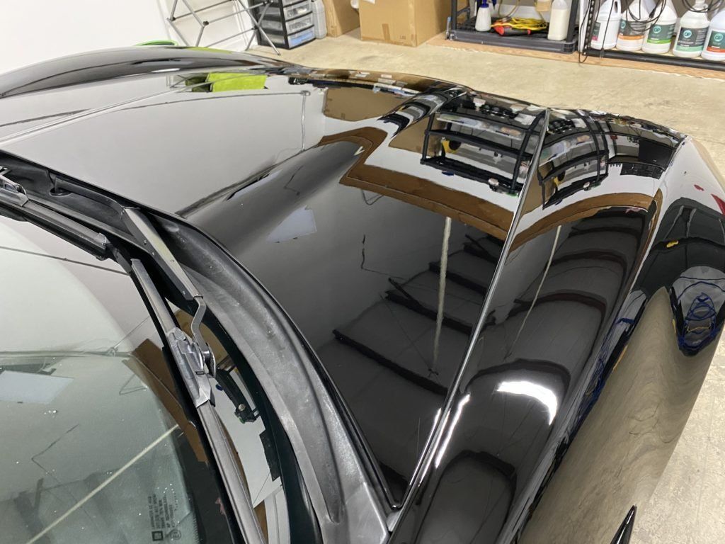 A close up of a black car 's hood in a garage.