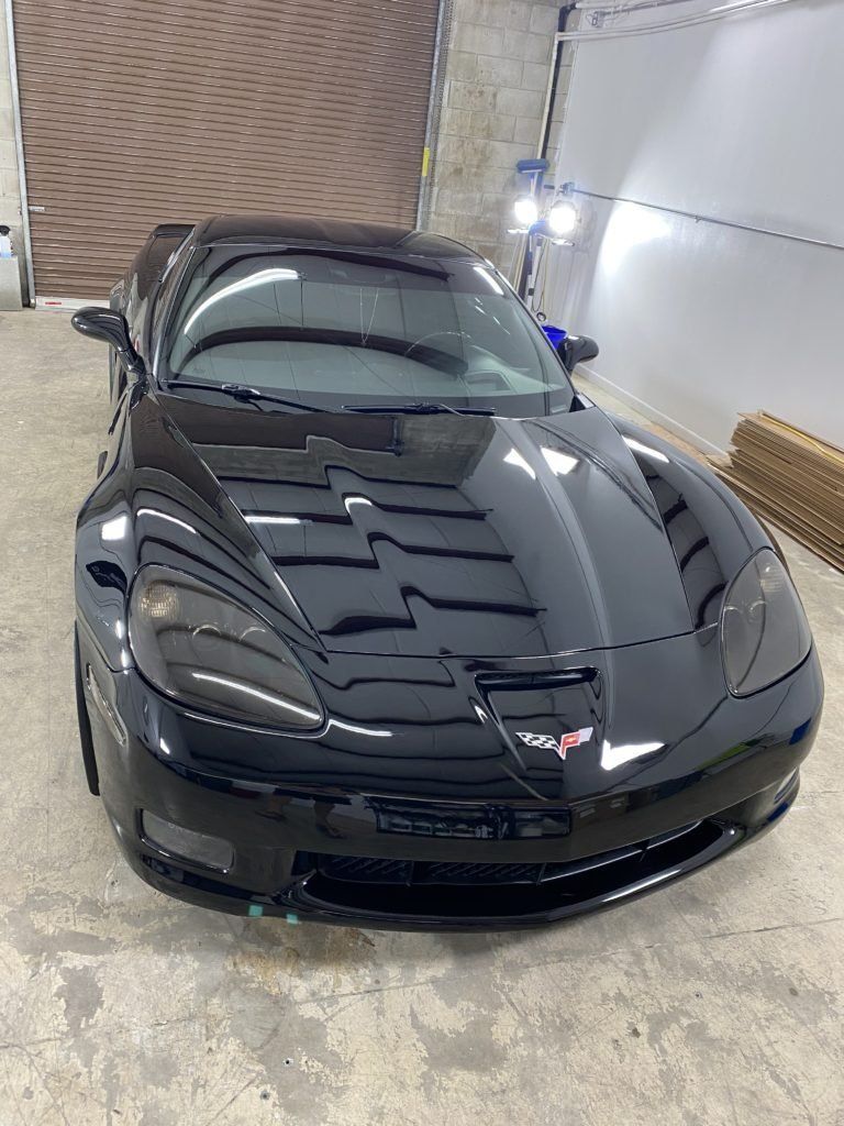 A black corvette is parked in a garage.