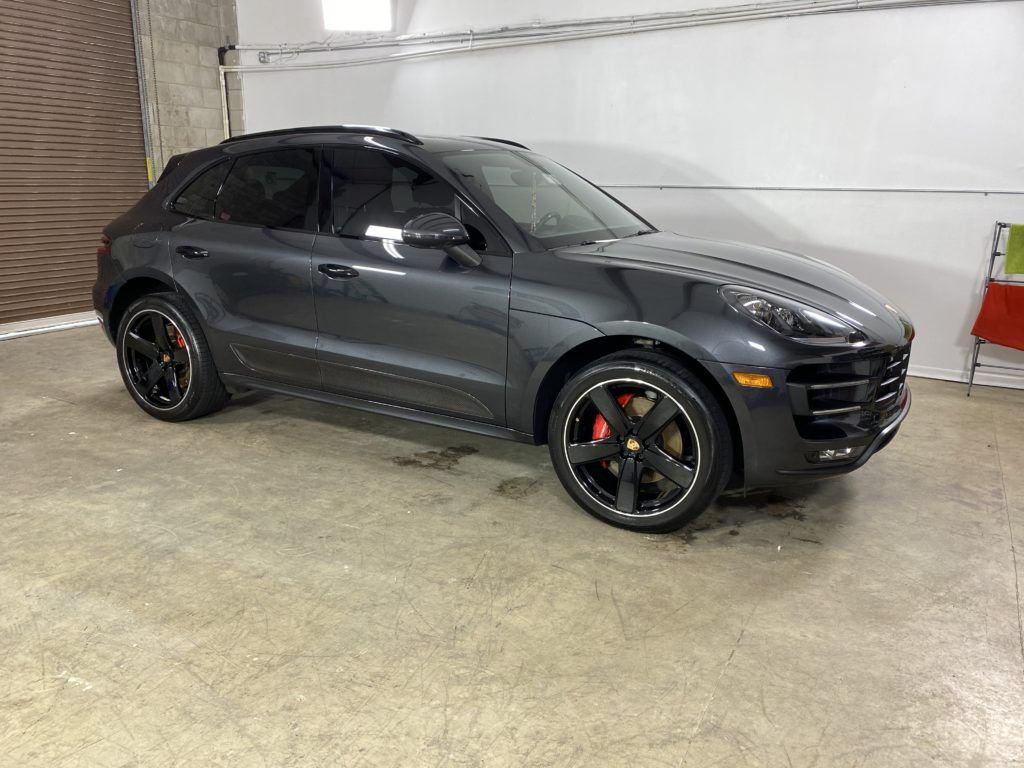 A gray porsche macan turbo is parked in a garage.
