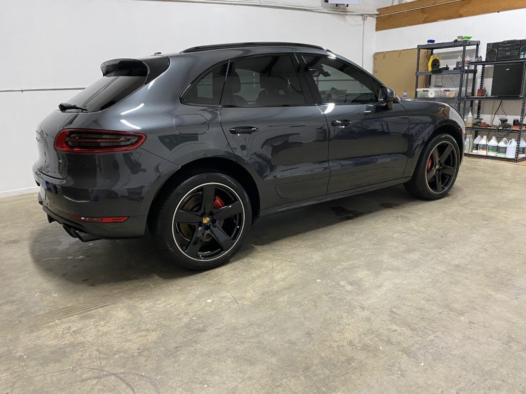 A gray porsche macan is parked in a garage.