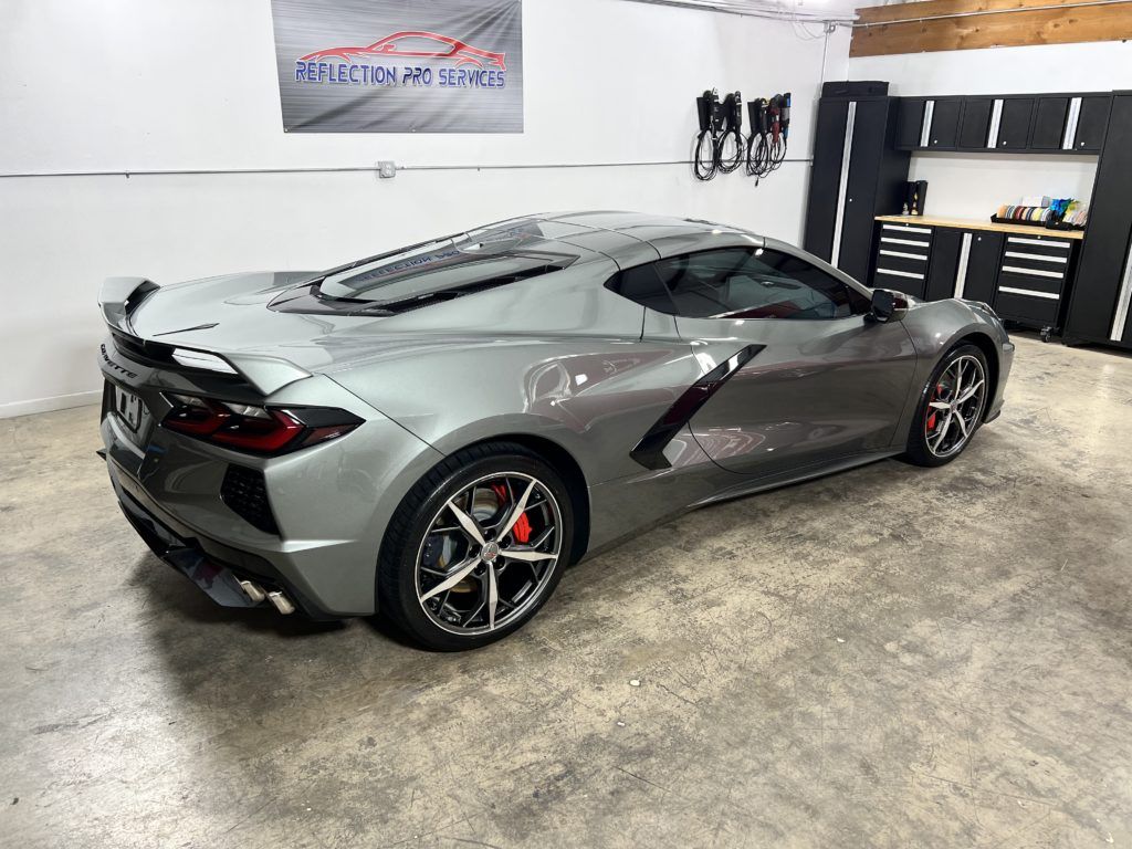 A gray sports car is parked in a garage.