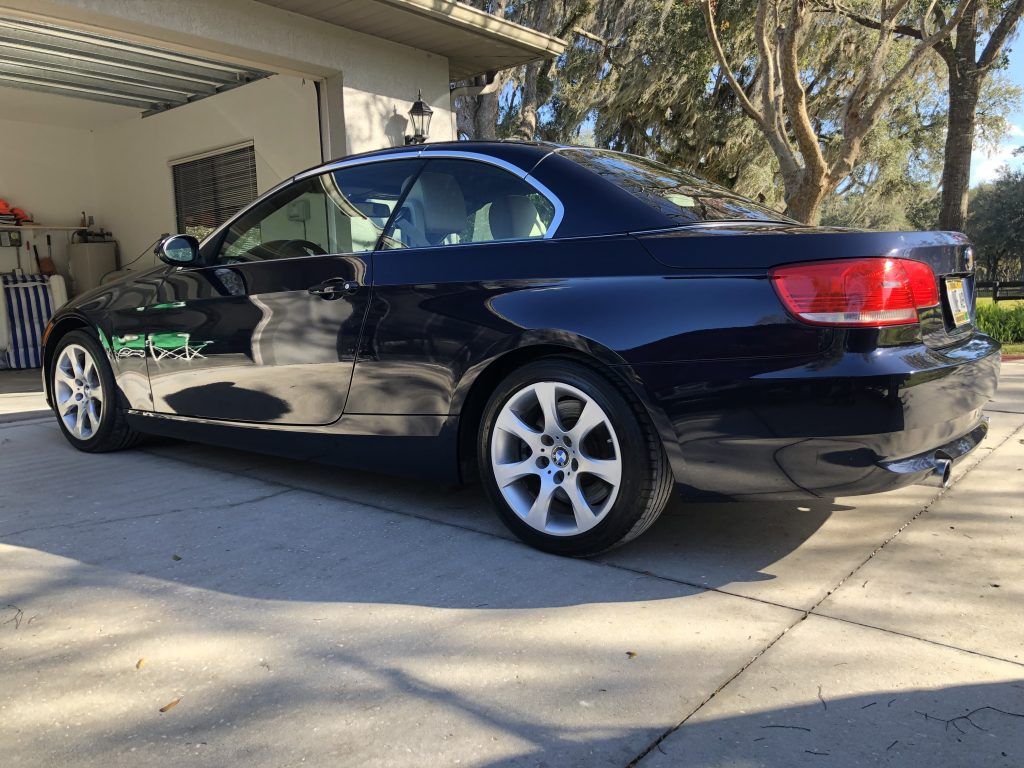 A black car is parked in a driveway next to a garage.