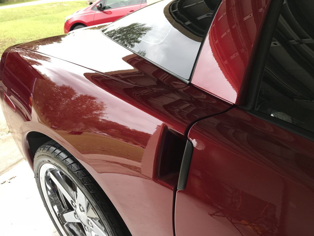 A red car is parked in a driveway next to a red car