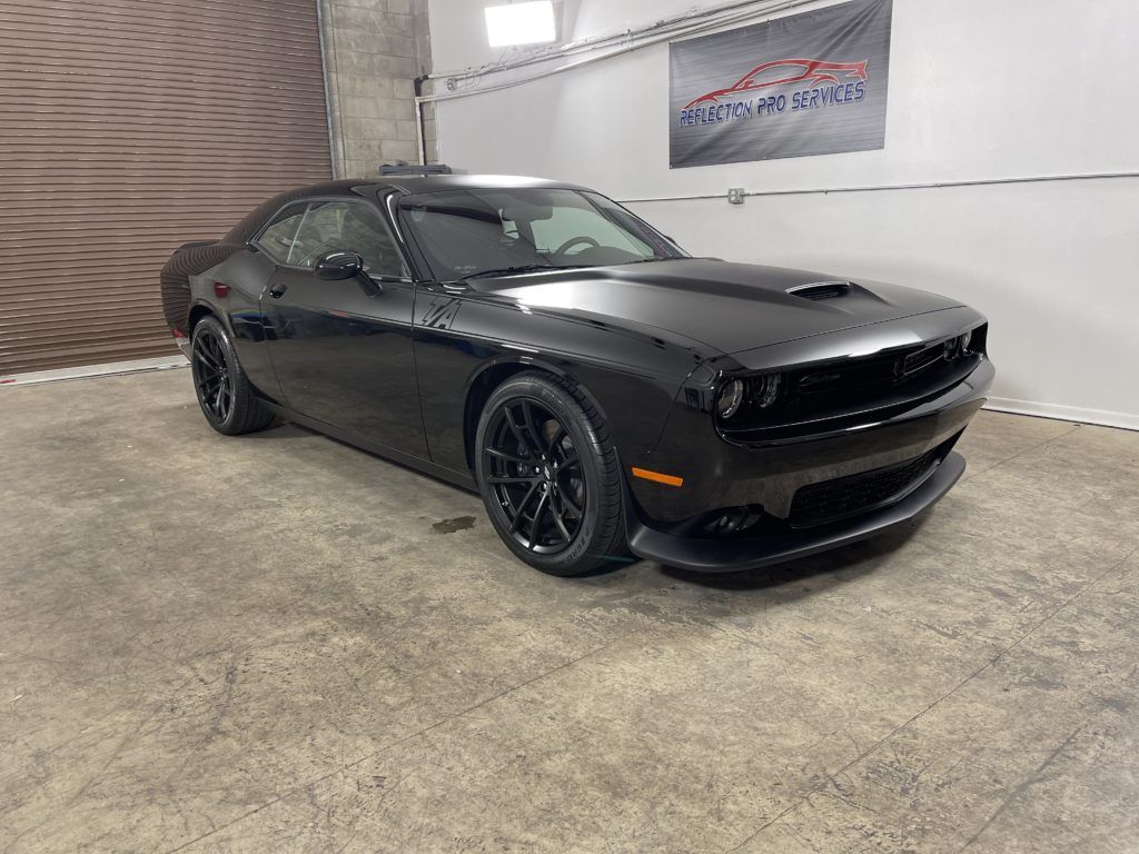A black dodge challenger is parked in a garage.