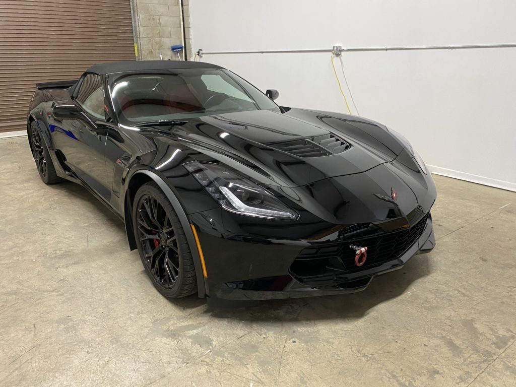 A black corvette zr1 convertible is parked in a garage.
