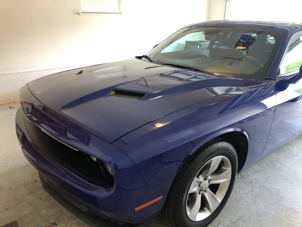 A blue dodge challenger is parked in a garage.