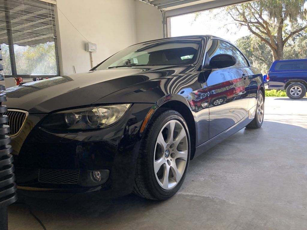 A black bmw 3 series coupe is parked in a garage.