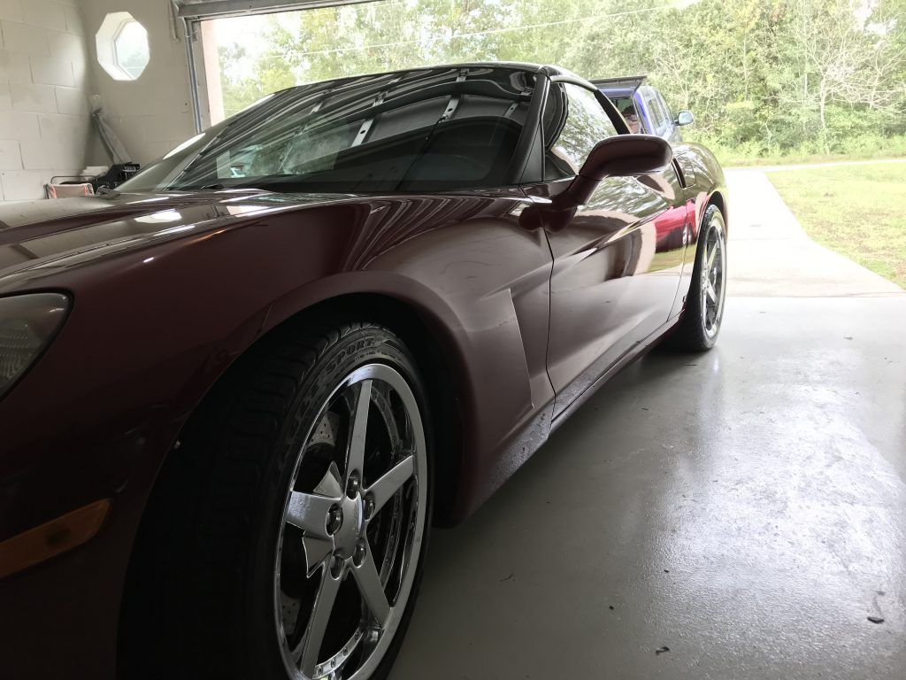 A red sports car is parked in a garage.