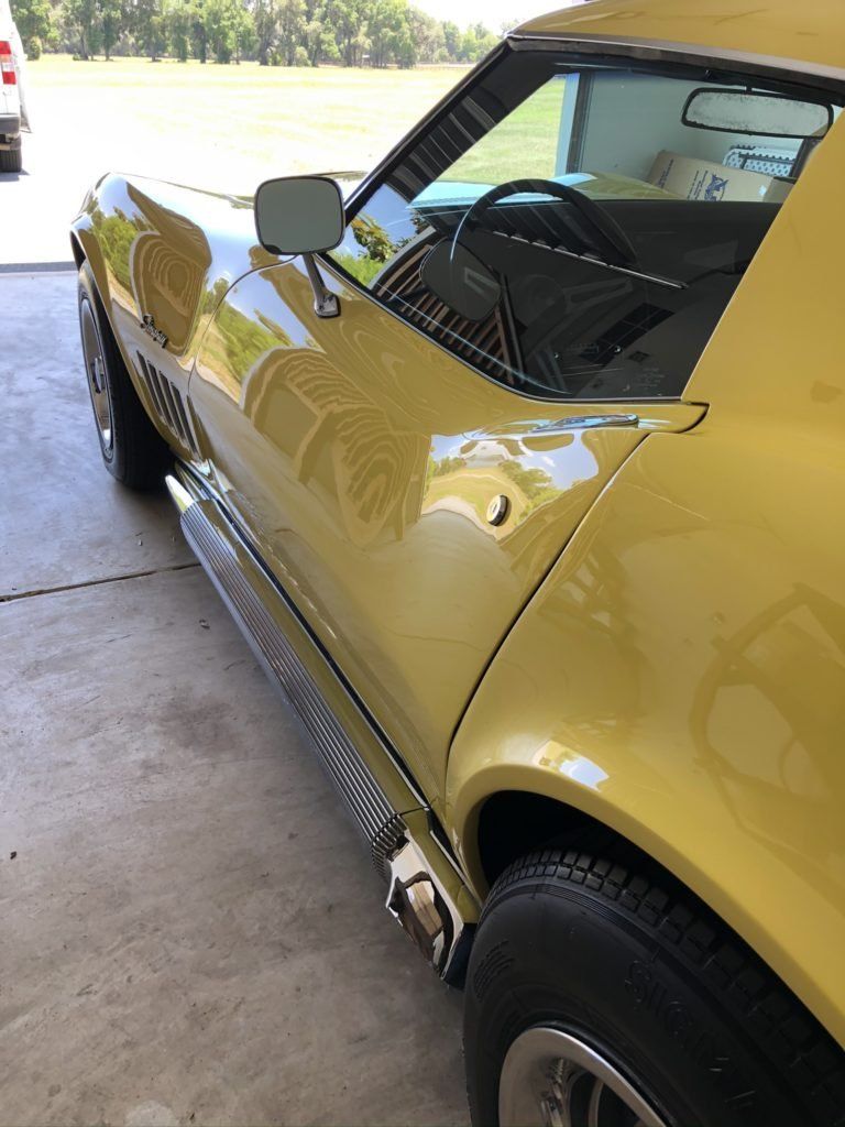 A yellow corvette is parked in a garage